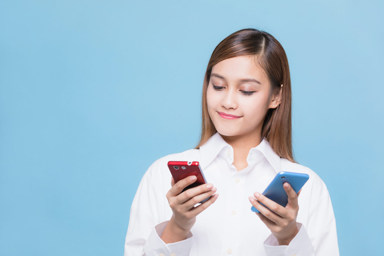 Young woman holding two smart phones.