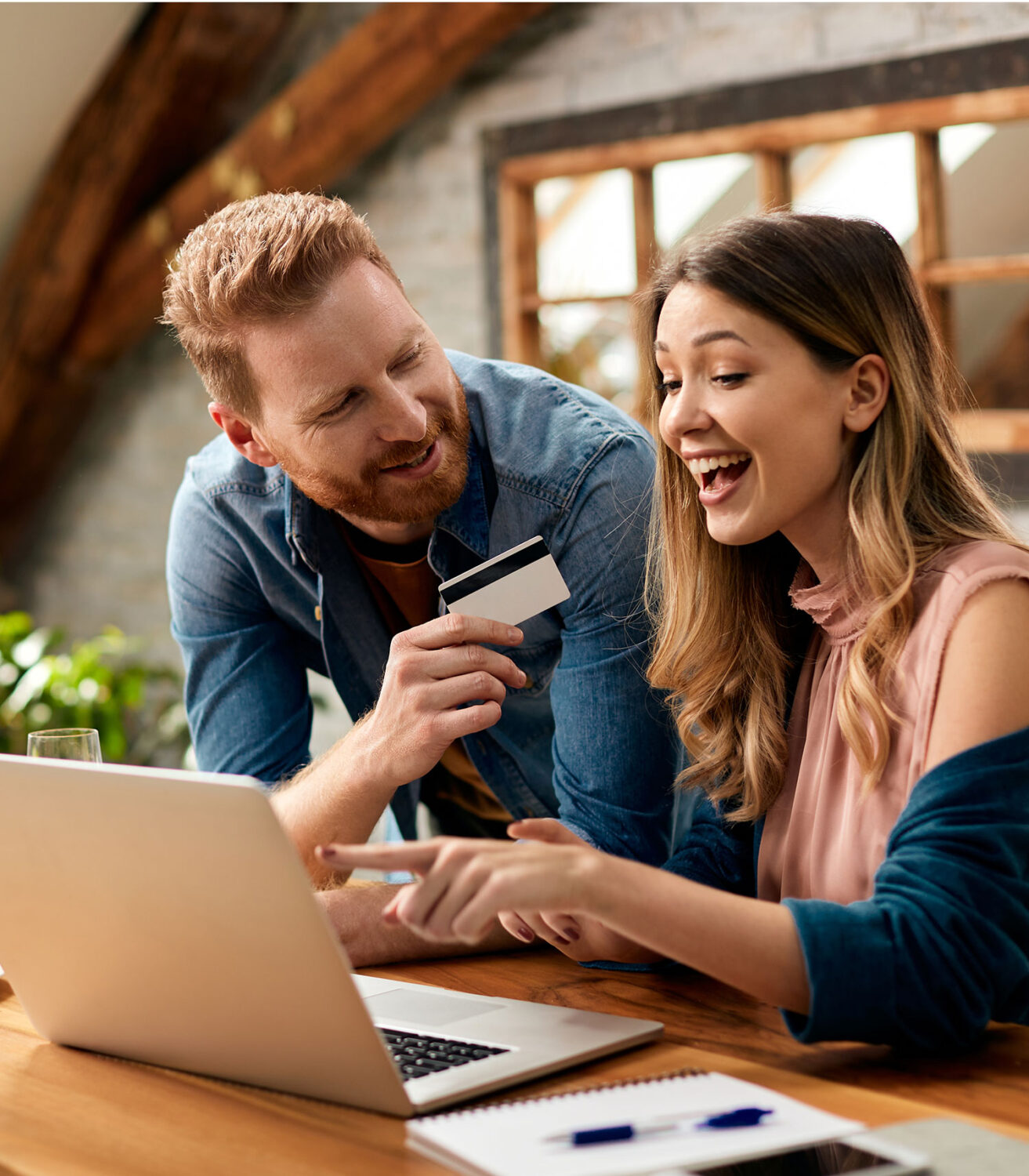 Man and woman with credit card smiling and pointing at laptop screen customer engagement marketing