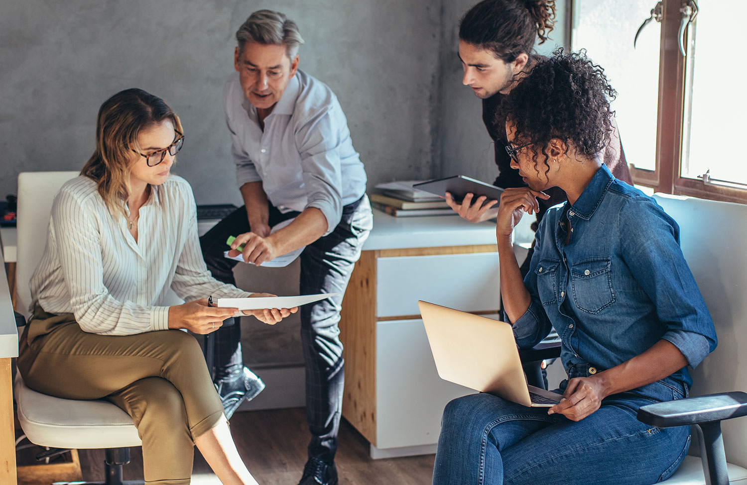 Four people looking at business materials in an office